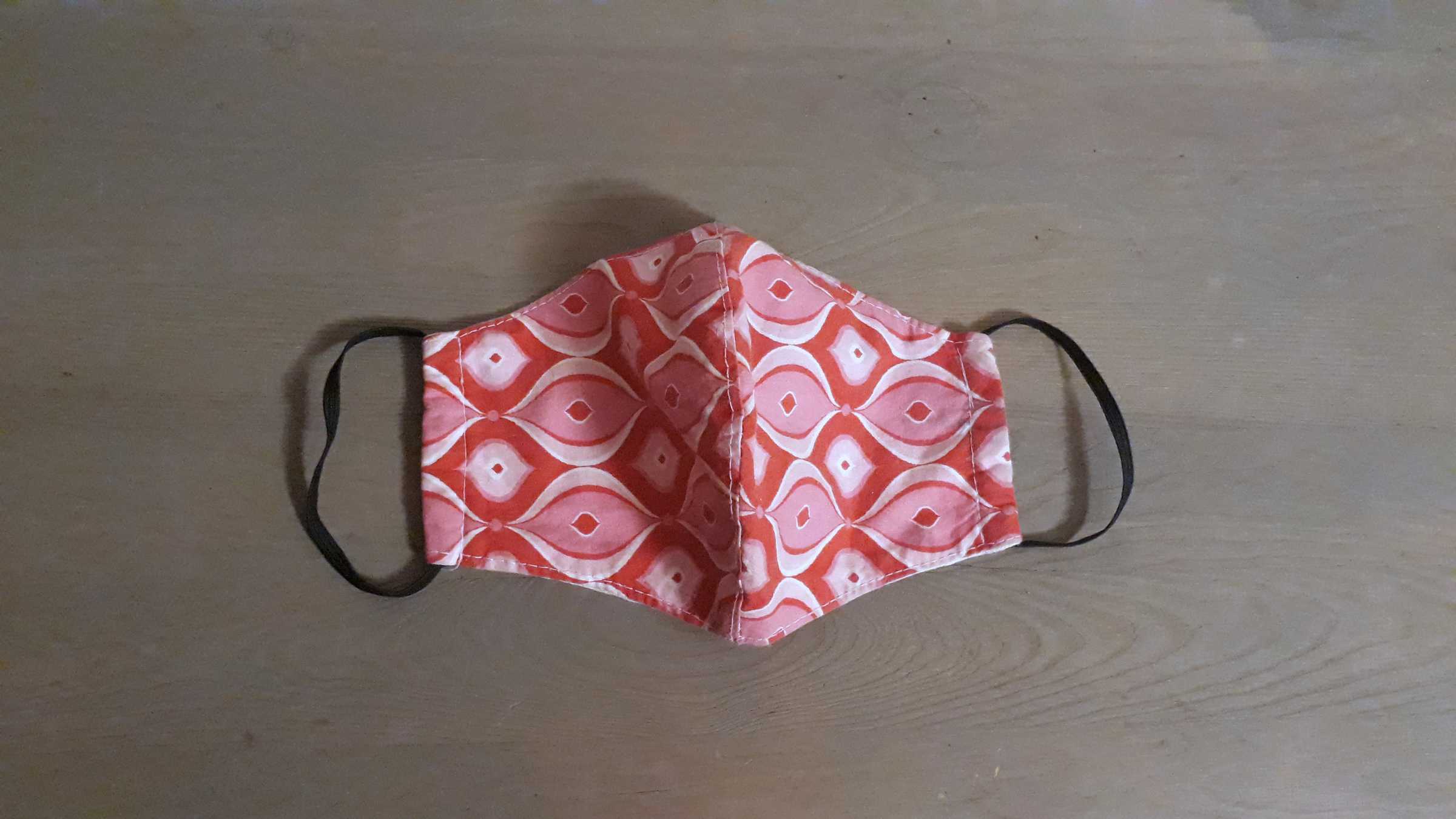 Corona-Objekt gemusterte Stoffmaske auf Holzoberfläche