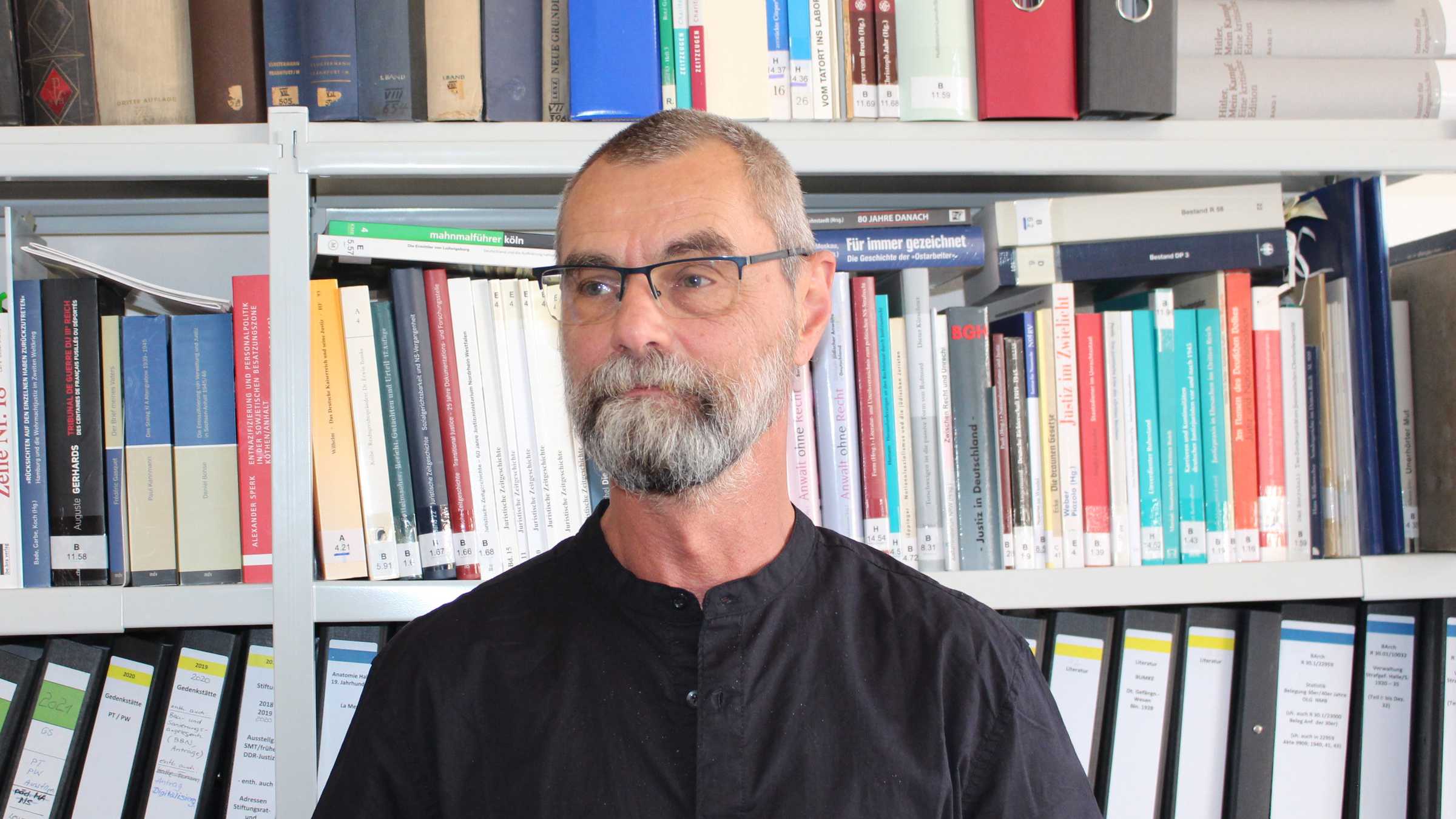 Portrait Michael Viebig vor einem Bücherregals