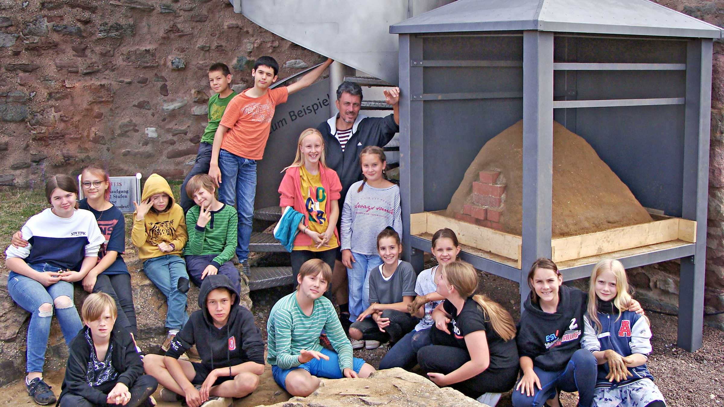 Die Kinder des Projekts posieren stolz mit ihrem selbstgebauten Lehmofen Die Kinder des Projekts posieren auf der Burg Giebichenstein. Rechts von ihnen ist der fertige Lehmofen in seiner Überdachung zu sehen.