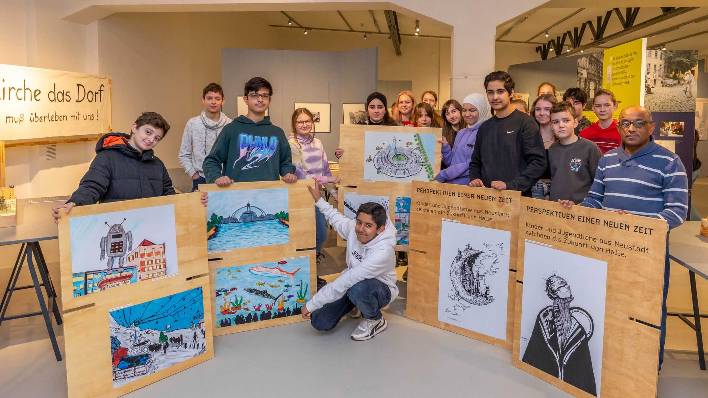 Jugendliche mit ihrer Ausstellung, Foto: Thomas Ziegler Gruppe von ca. 15 Jugendlichen im Ausstellungsraum präsentieren ihre auf Sperrholzplatten aufgeklebten Bilder