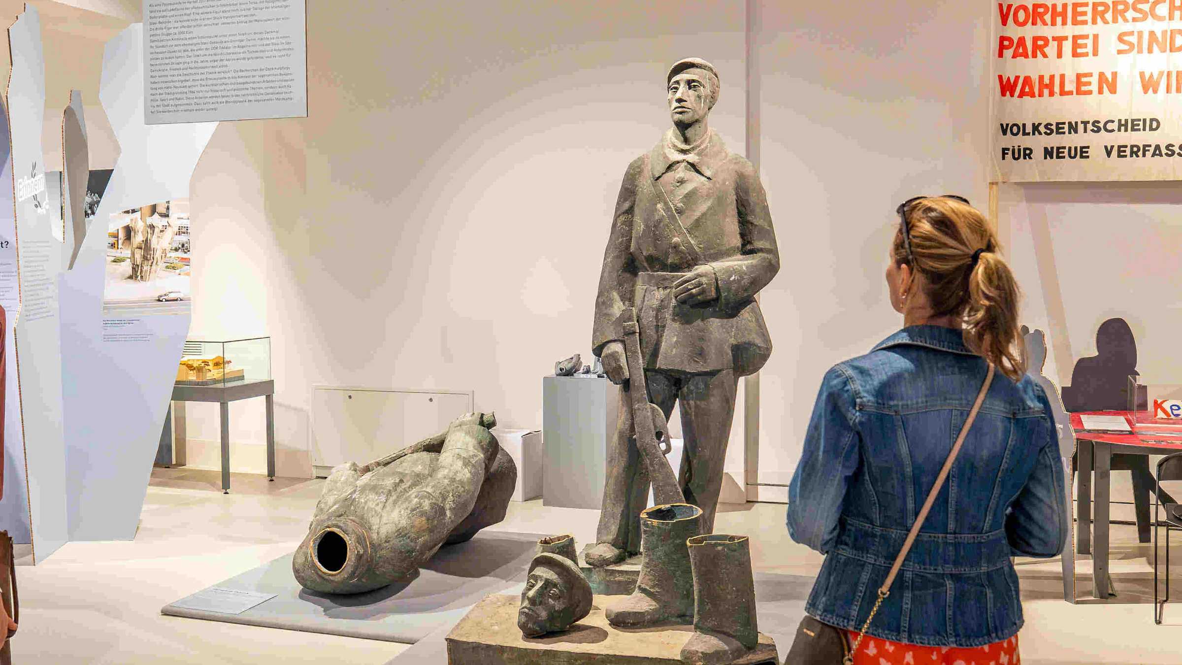 zerstörte Märkkämpfergruppe eine Frau steht vor einem Denkmal in der Ausstellung Streit, Zoff und Beef