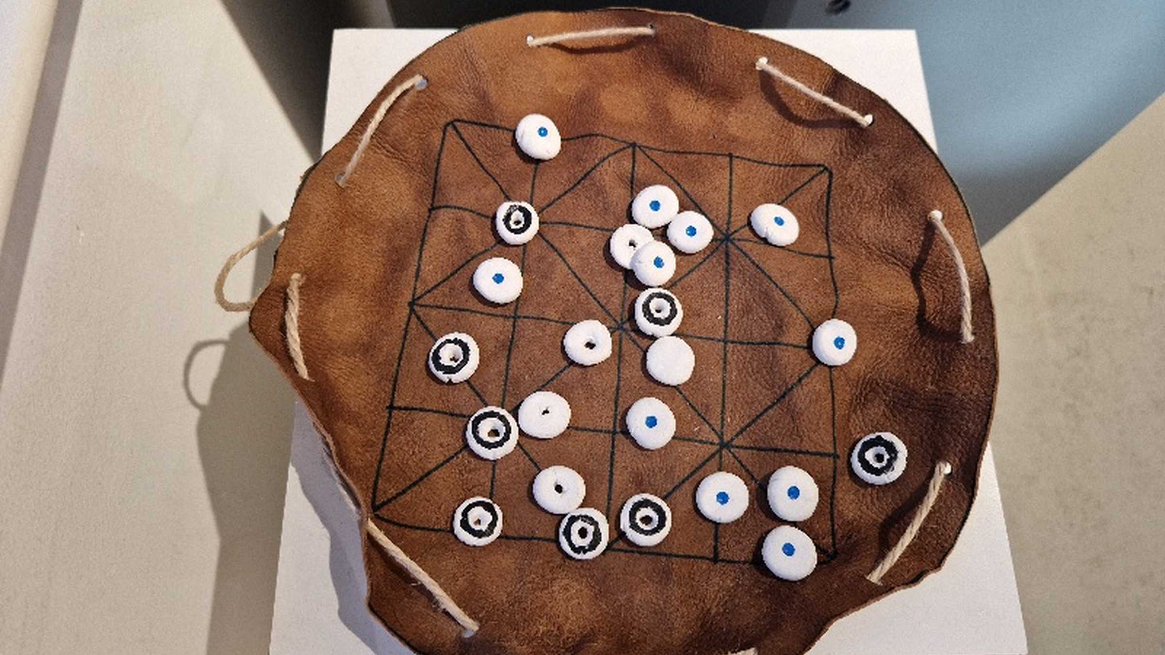 Alquerque runde Spielsteine auf ausgebreitetem Lederbeutel