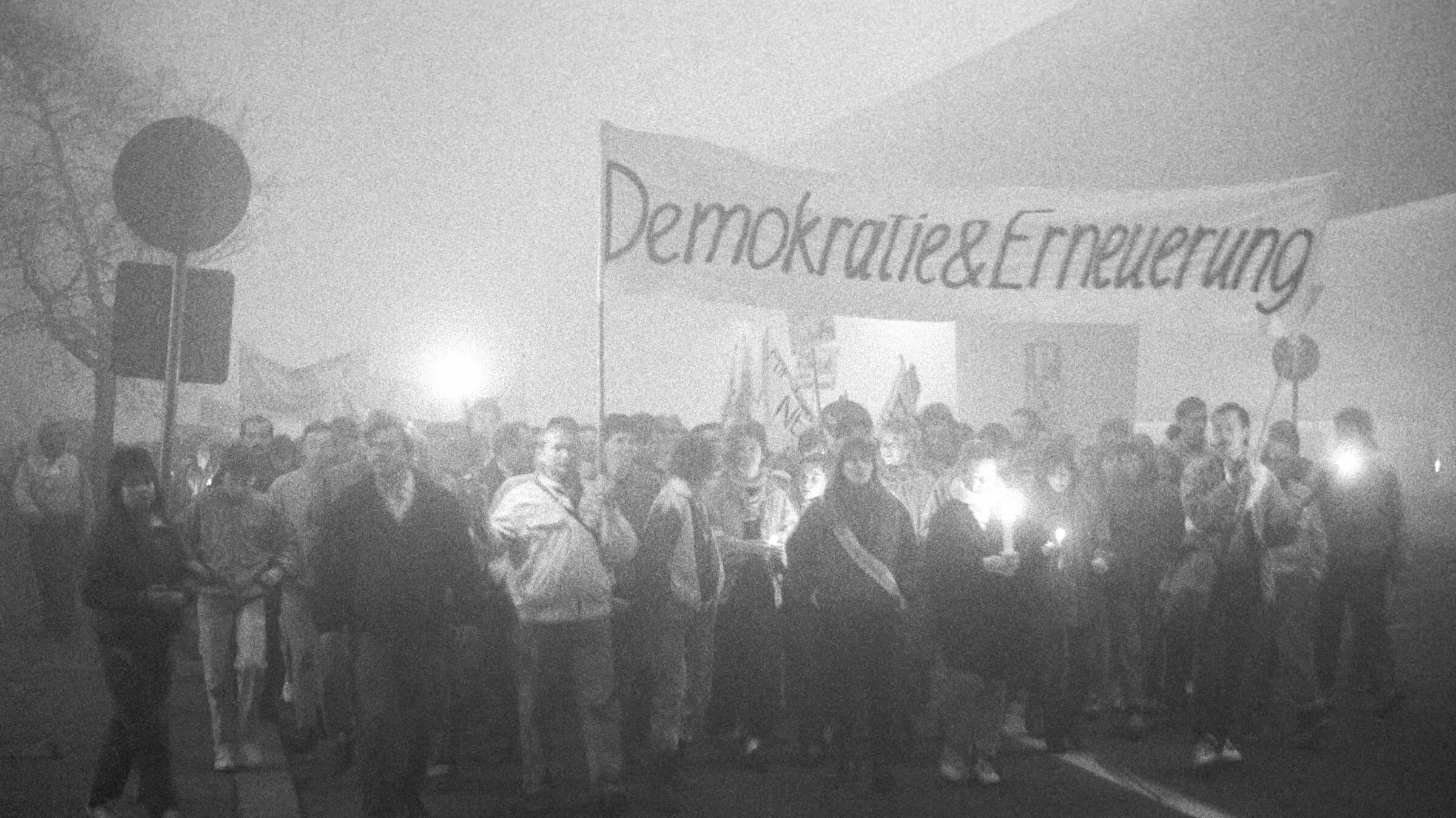 Demonstrationszug an einem nebligen Abend auf dem Franckeplatz, auf einem Banner steht "Demokratie und Erneuerung" 