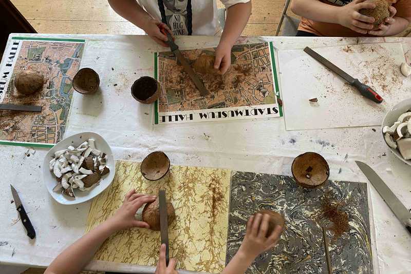 Kinder bearbeiten die schalen von Kokosnüssen