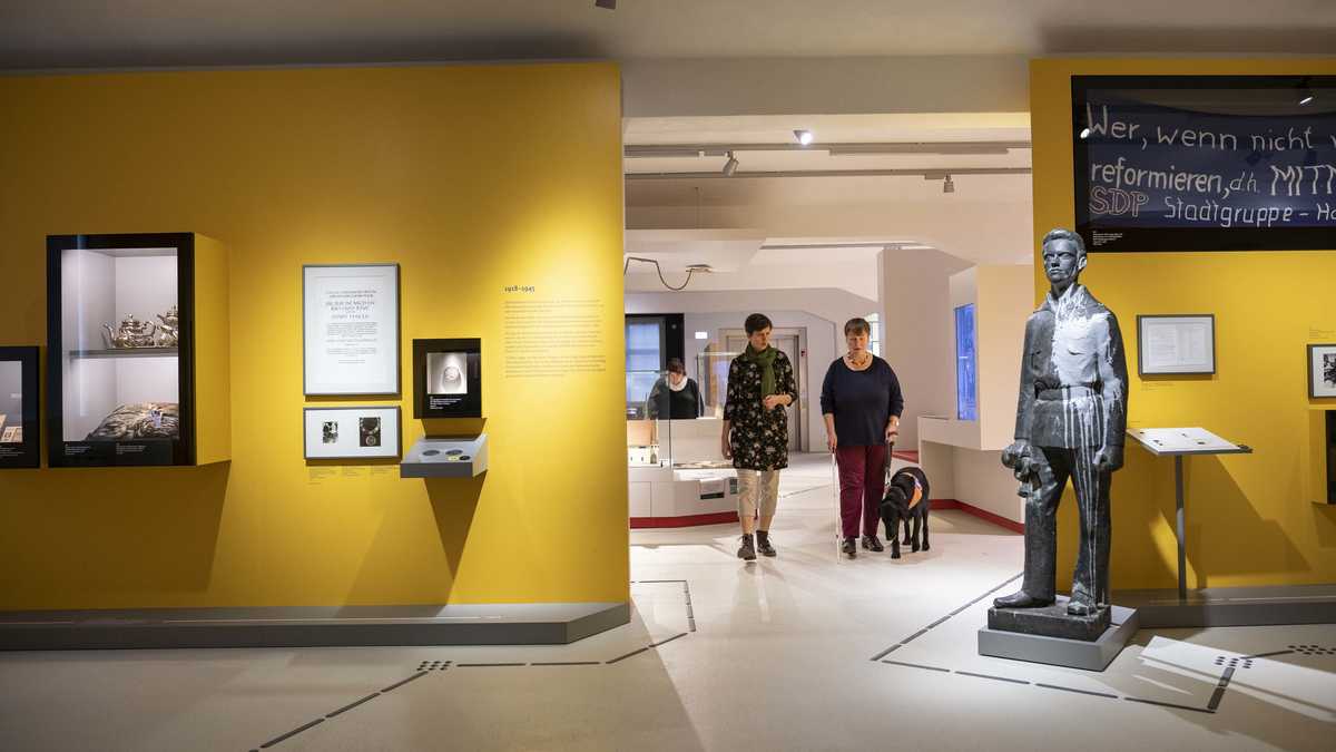Blick in die Ausstellung und auf Frau mit einem Begleithund