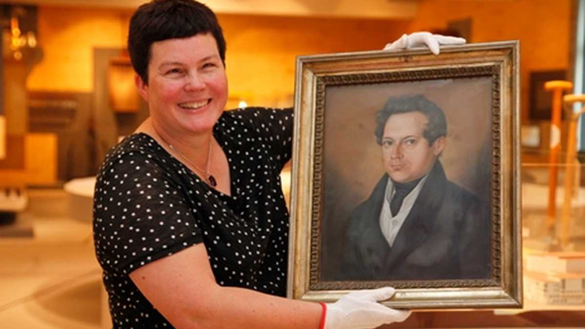 Jane Unger (die Direktorin des Museums), die lachend ein Portrait in ihren Händen hält