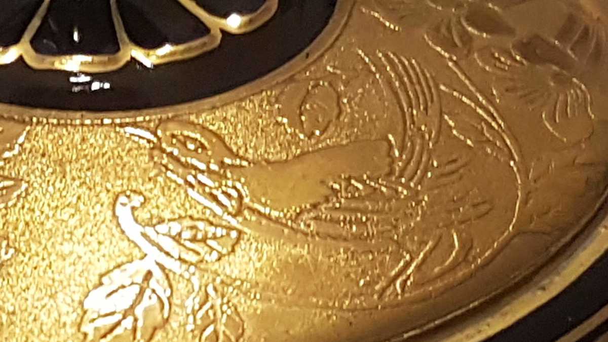 Goldverzierung Detail Deckel mit geätztem Goldmotiv in Form eines Vogels