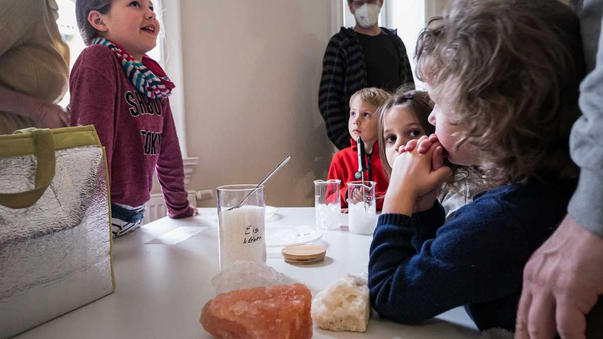 Experimente mit Salz Kinder stehen um einen Tisch und experimentieren mit Salzklumpen