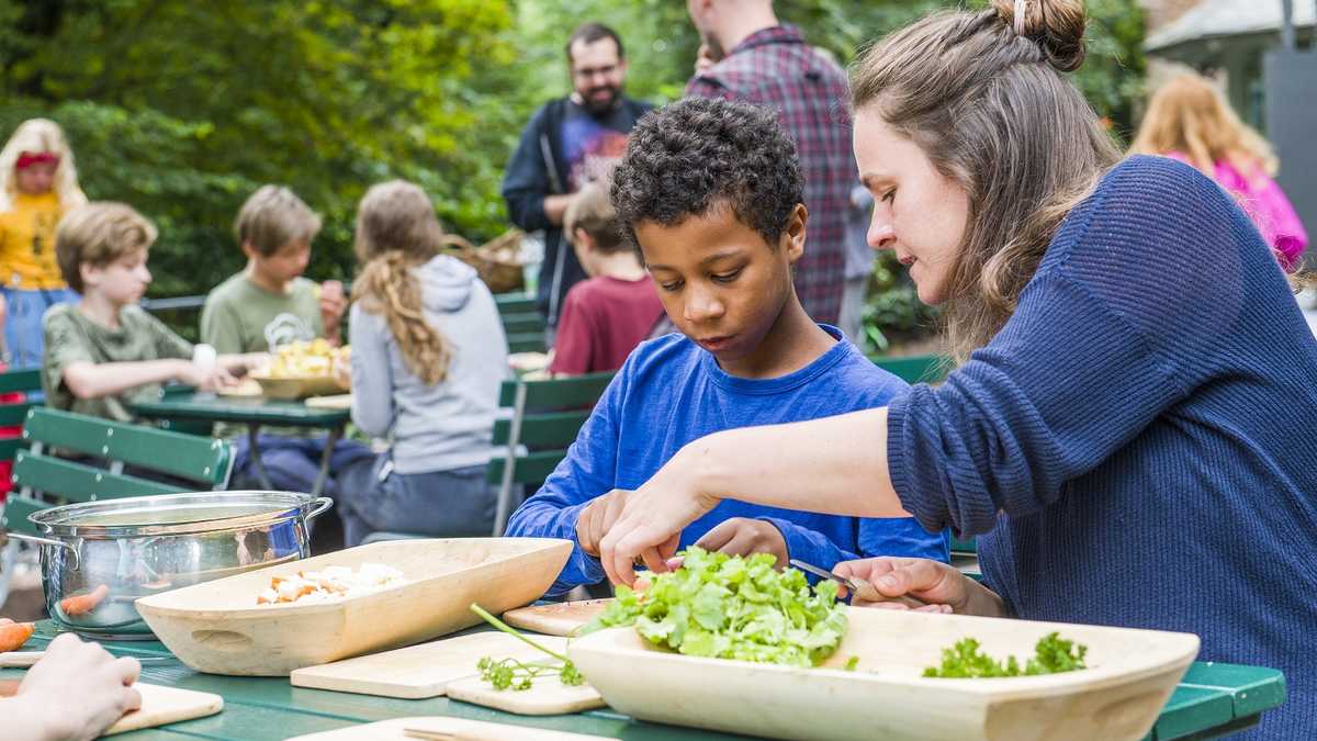 Mittelalterliche Küche Kinder schneiden draußen Gemüse und Kräuter in Holzgefäße