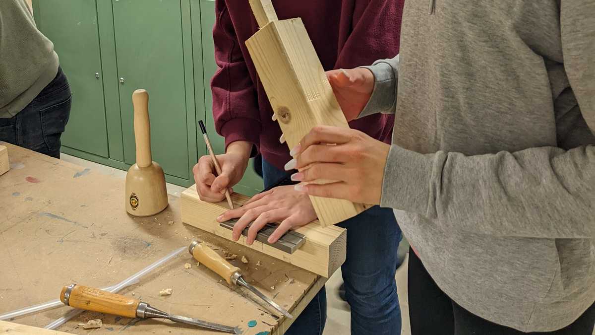 Jugendliche bei der Erstellung von Holzverbindungen. Zwei Jugendliche bauen Holzverbindungen.