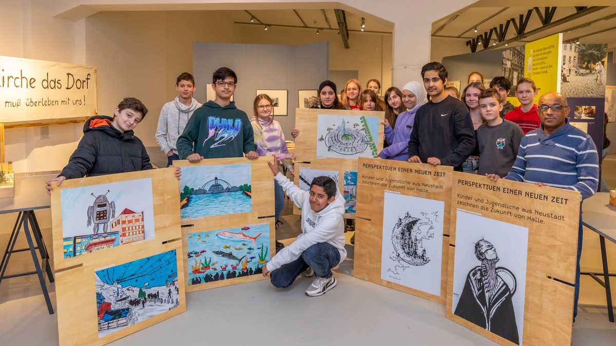 Jugendliche mit ihrer Ausstellung, Foto: Thomas Ziegler Gruppe von ca. 15 Jugendlichen im Ausstellungsraum präsentieren ihre auf Sperrholzplatten aufgeklebten Bilder