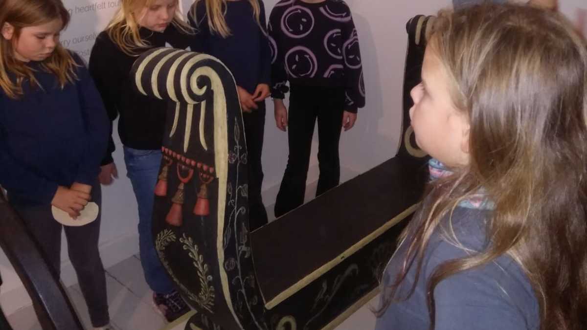 Schlitten im Christian-Wolff-Haus Kinder stehen um einen barocken Schlitten in der Ausstellung