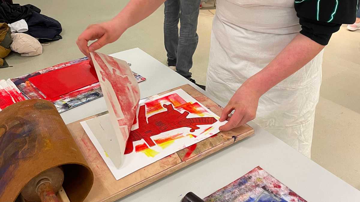 Jugendlicher zieht ein Druckwerk vom Druckstock