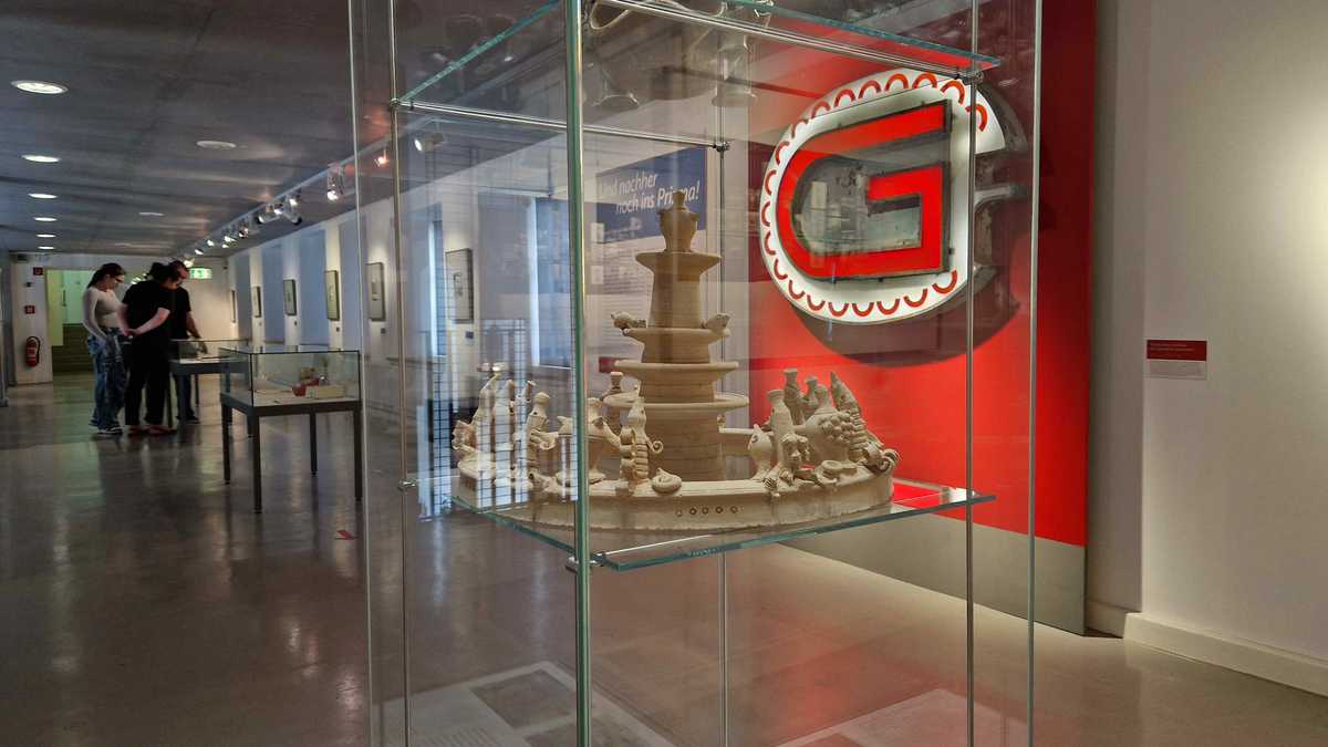 Blick in die Ausstellung, im Vordergrund ein Tonmodell des Meeresbrunnens, im Hintergrund der Buchstabe G der Leuchtwerbung Gastronom