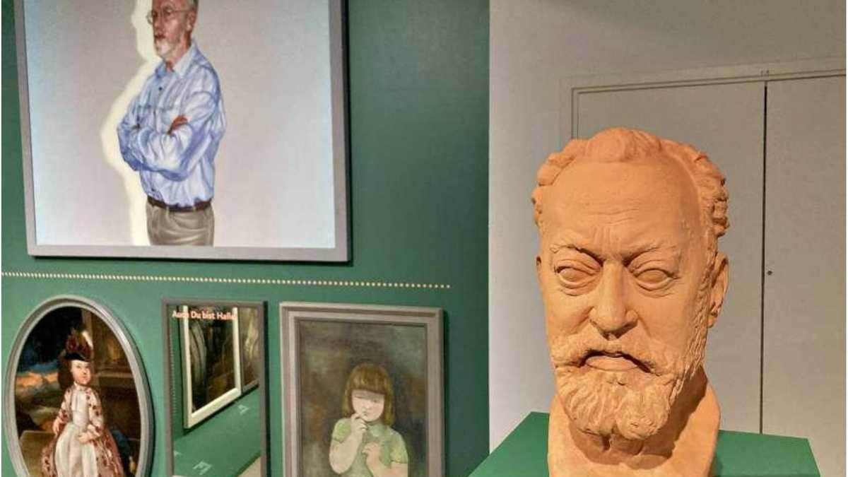 Rechts Statue auf einem Tisch, links verschiedene Gemälde an einer grünen Wand