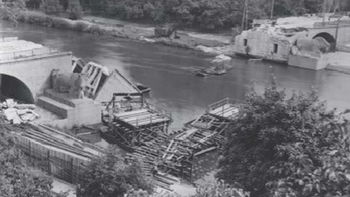 zerstörte Kröllwitzer Brücke darunter ein Fluss teilweise verdeckt durch Bäume