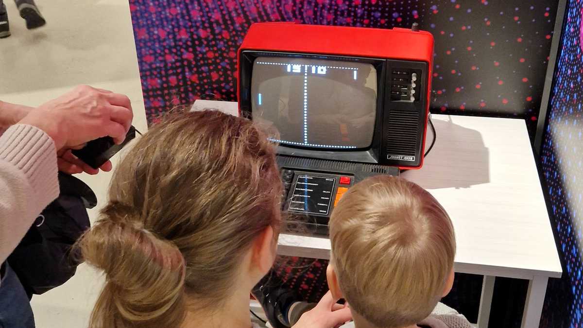Eine Frau und ein Kind spielen das Bildschirmspiel Teletennis