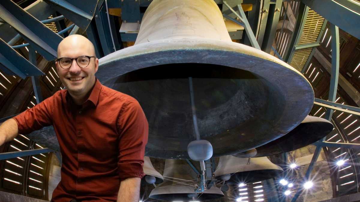Mann mit rotem Hemd vor Glocken