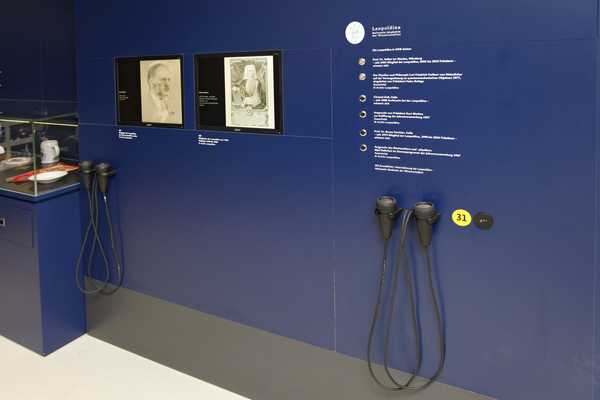 Blick in eine Ausstellung. Vordergründig sind die leicht zu erreichenden Audioguides zu sehen
