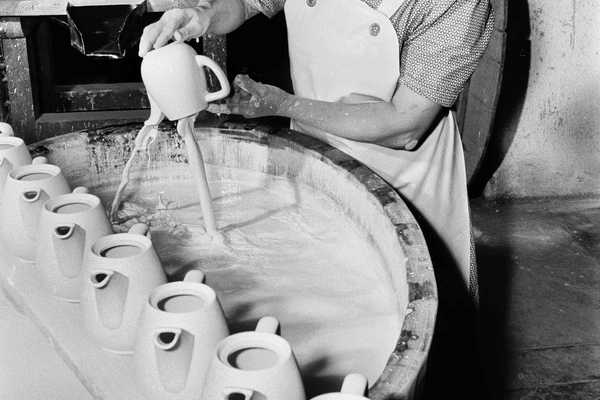 schwarz-weiß-Foto mit einer Arbeiterin am Glasurbecken