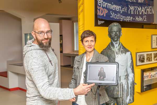 Henry Niekrawietz mit dem Tablet und Elke Arnold vom Stadtmuseum vor der Skulptur des Kleinen Trompeters