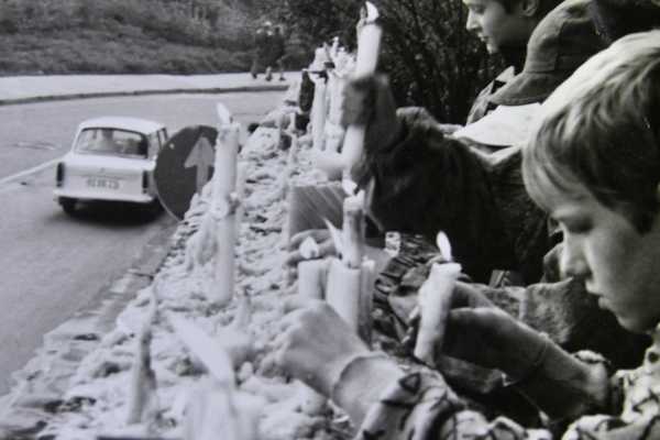 Kinder und Jugendliche stellen brennende Kerzen auf die Mauer an der Georgenkirche