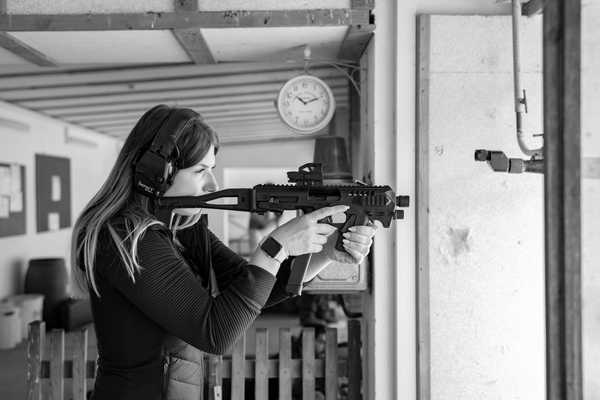 eine junge Frau mit einer modernen Schusswaffe am Schießstand