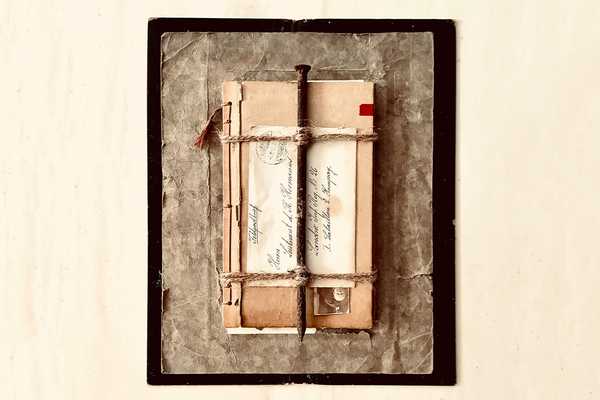Materialcollage mit Notizbuch, historischen beschrifteten Brief und einem großen rostigem Nagel