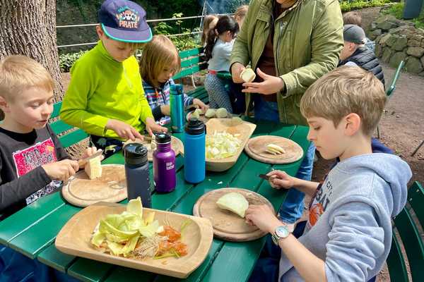 Kinder bereiten am Tisch die Gemüsesuppe vor