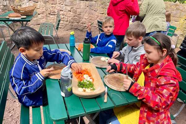 Kinder bereiten am Tisch die Gemüsesuppe vor