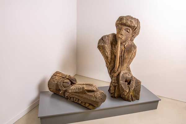 aus Baumstämmen geschnitzte Figuren Drachenkopf und Flötenspieler