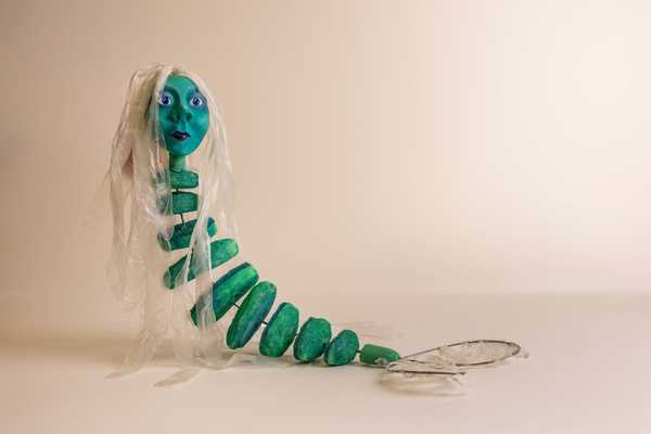 Figur mit grünem segmentierten Körper, Menschenkopf und Schwanzflosse