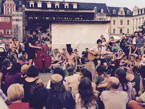 The Coins (Lisa Ossowski) Die drei Bandmitglieder vor einer Bühne, viele Zuschauer um sie herum