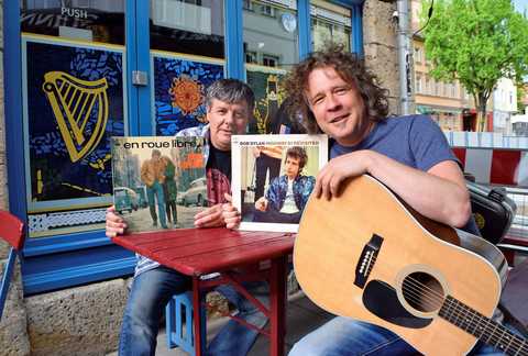 BOB DYLAN TRIBUTE „FOREVER YOUNG“ Die zwei Mitglieder der Band halten Bob Dylan Platten in die Kamera. Einer hat eine Gitarre auf dem Schoß