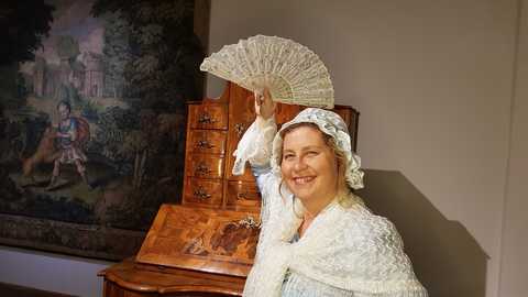Führung mit Freifrau von Wolff Frau Wolff im historischen Kleid mit erhobenem Fächer im Empfangsraum