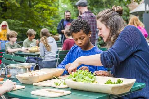 Mittelalterliche Küche Kinder schneiden draußen Gemüse und Kräuter in Holzgefäße