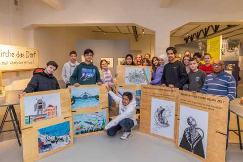 Jugendliche mit ihrer Ausstellung, Foto: Thomas Ziegler Gruppe von ca. 15 Jugendlichen im Ausstellungsraum präsentieren ihre auf Sperrholzplatten aufgeklebten Bilder