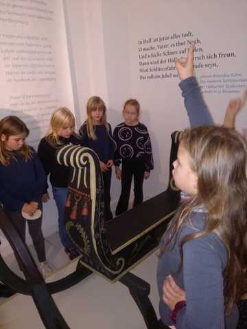 Schlitten im Christian-Wolff-Haus Kinder stehen um einen barocken Schlitten in der Ausstellung