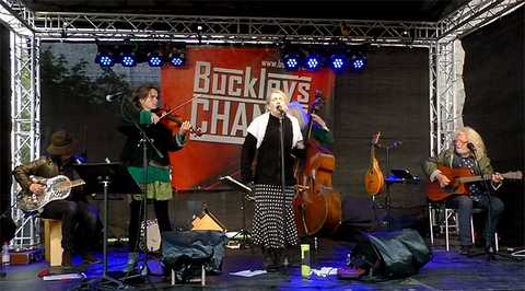 Buckleys Chance Foto der Band bei einem Auftritt. Sängerin Rebecca Didt singt am Mikrofon. Alex Wurlitzer spielt die Gitarre. Magdalena Wurlitzer an der Violine. Peter Häseler am Kontrabass und Michael Proschek an der Gitarre.